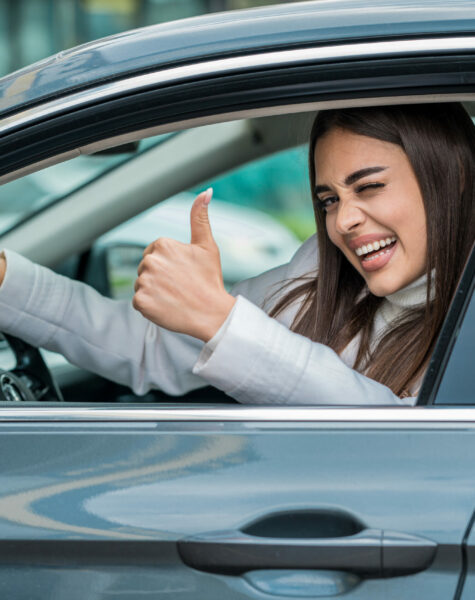 An attractive female posing behind the wheel of her car